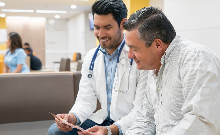 A male doctor and male patient smiling and reviewing care options together. 